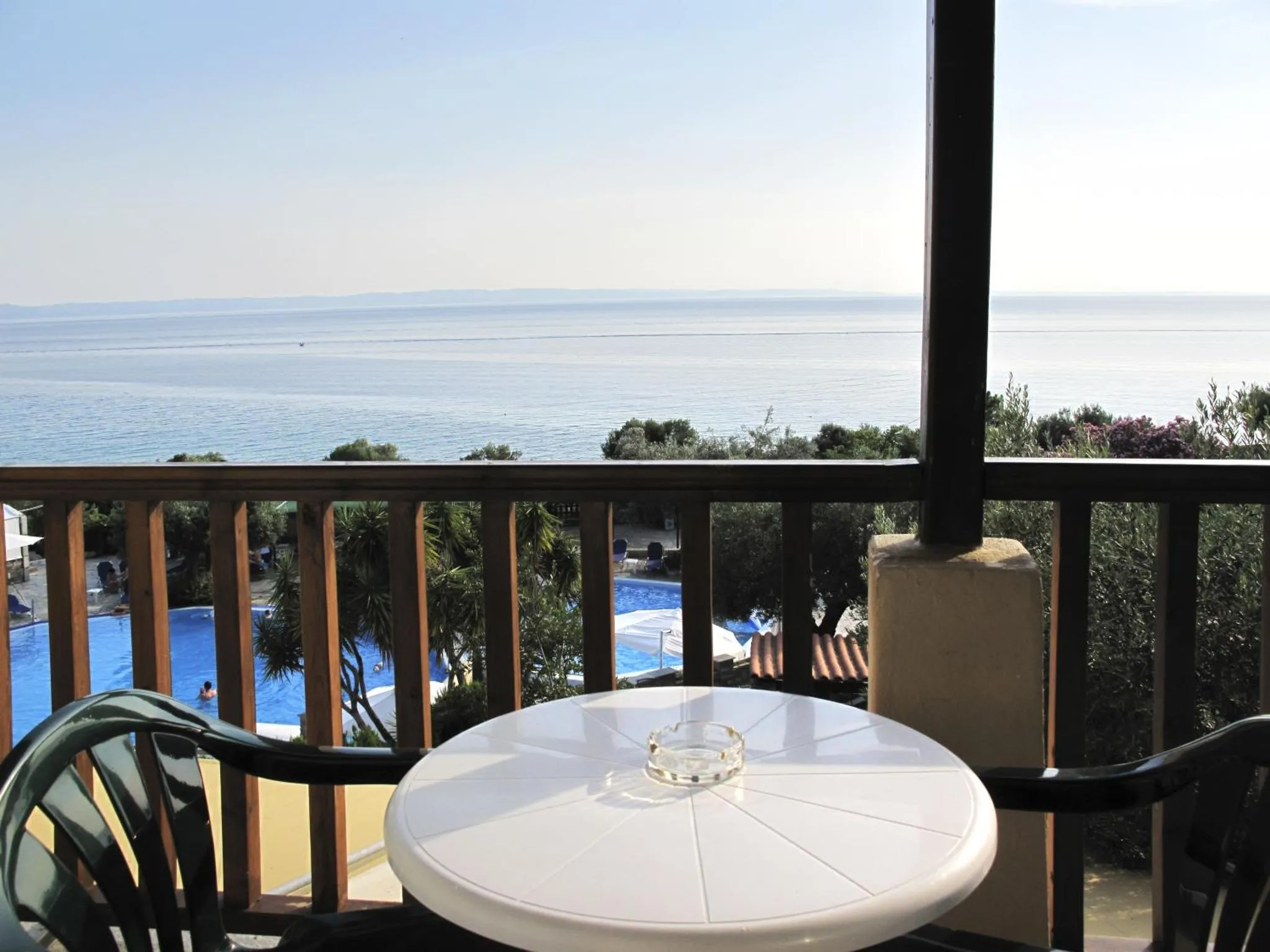 Vue d'une terrasse avec une table et des chaises donnant sur la mer et une piscine.