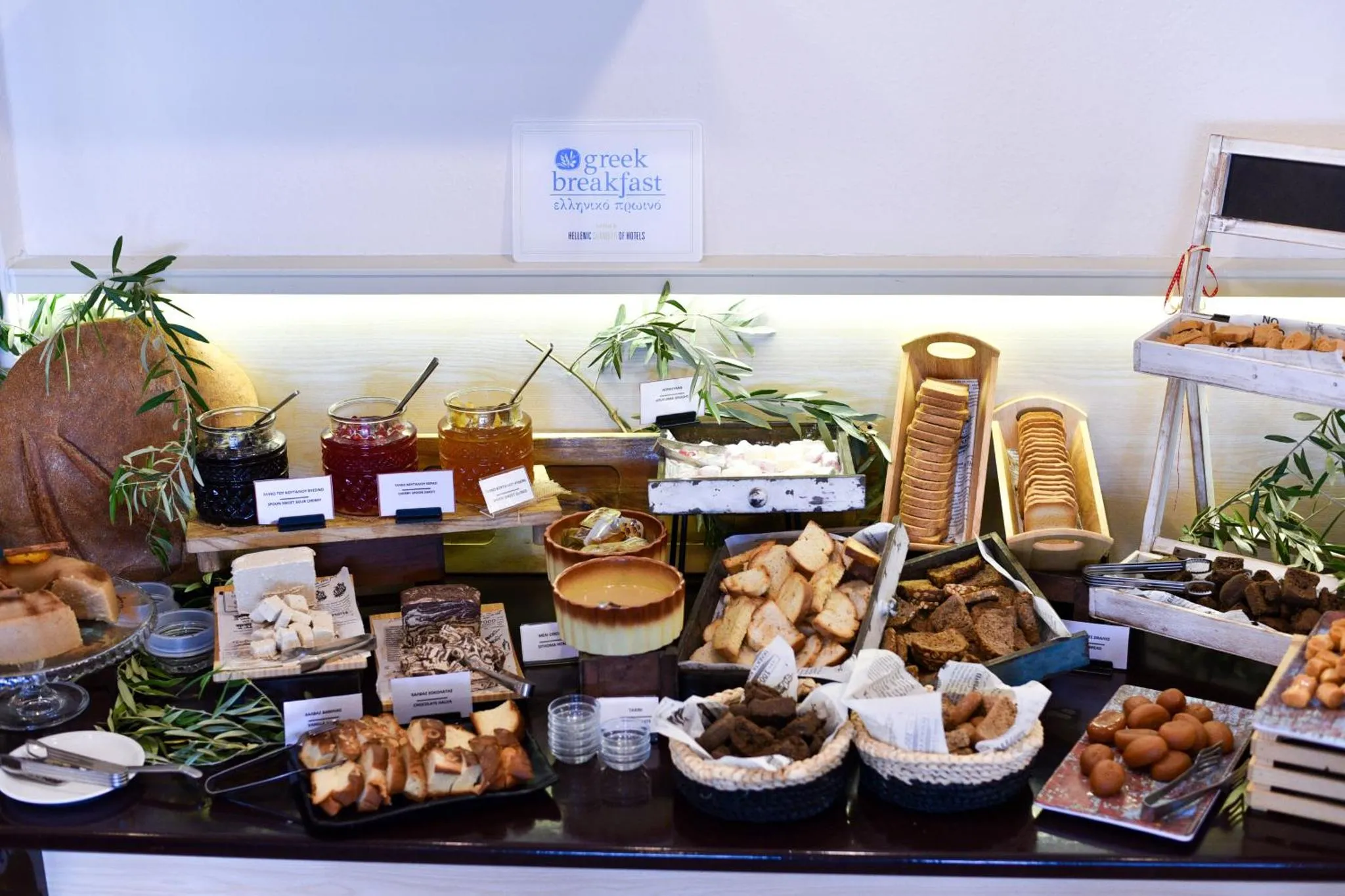 Un buffet propose une variété de pains, de fromages, de confitures et de pâtisseries.
