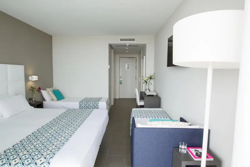 Chambre lumineuse avec deux lits et une décoration sobre.