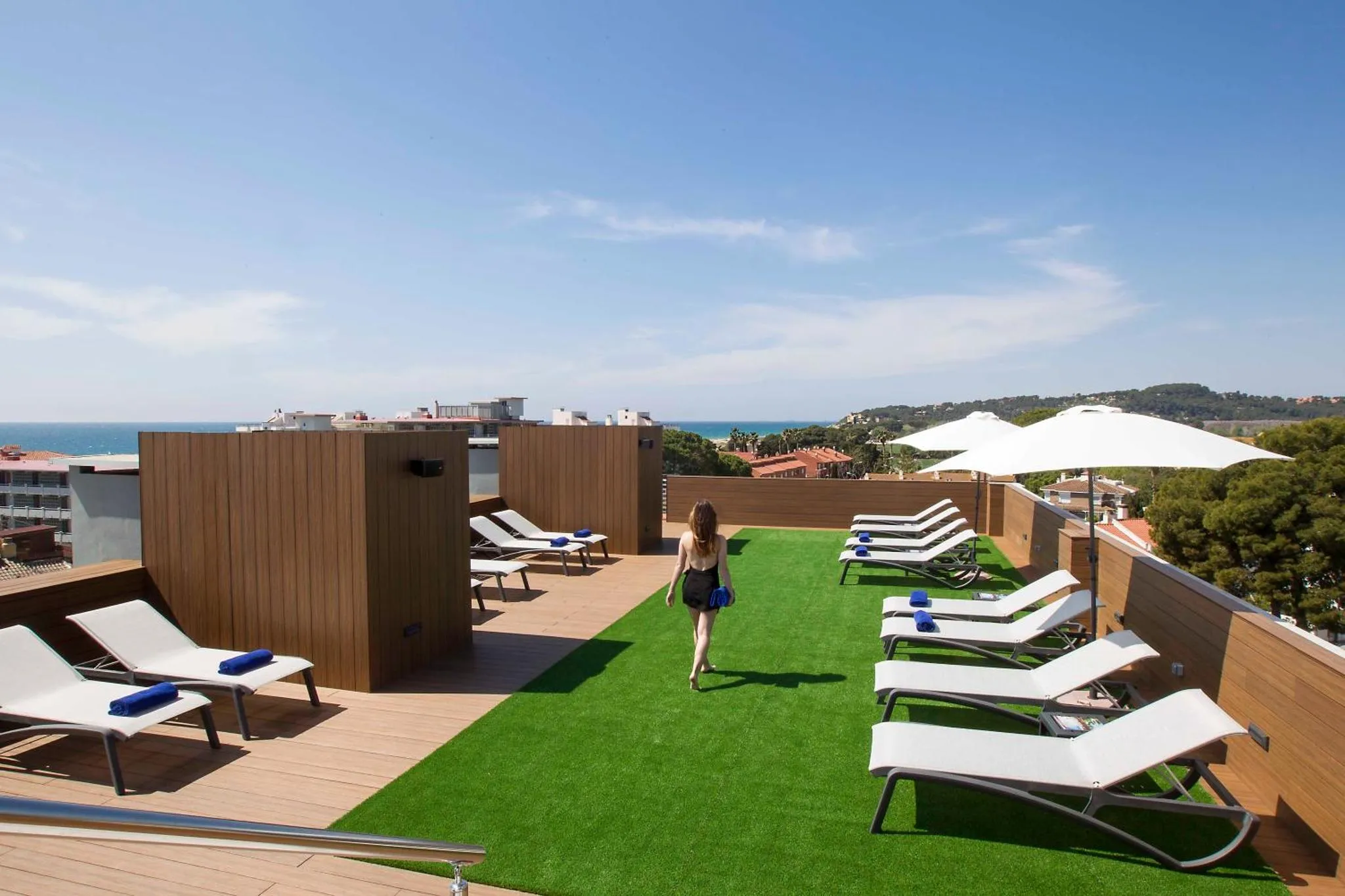 Terrasse aménagée avec transats et gazon synthétique offrant une vue sur la mer.