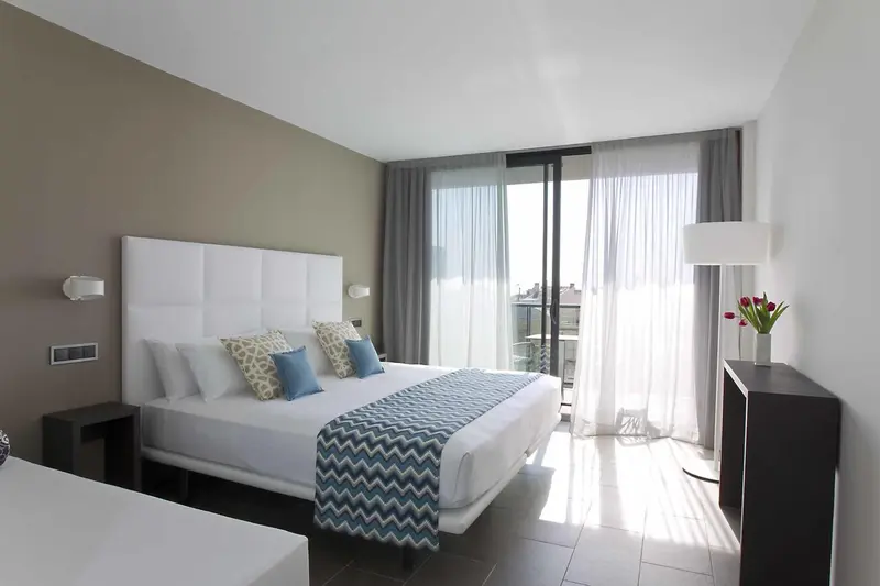 Une chambre lumineuse avec un grand lit et un accès à une terrasse.