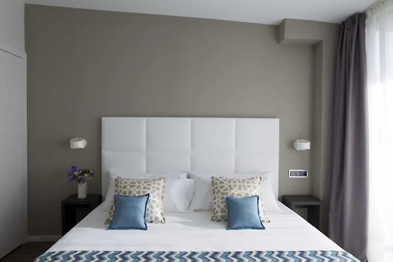 Une chambre avec un grand lit recouvert d'une courtepointe blanche et de coussins décoratifs.