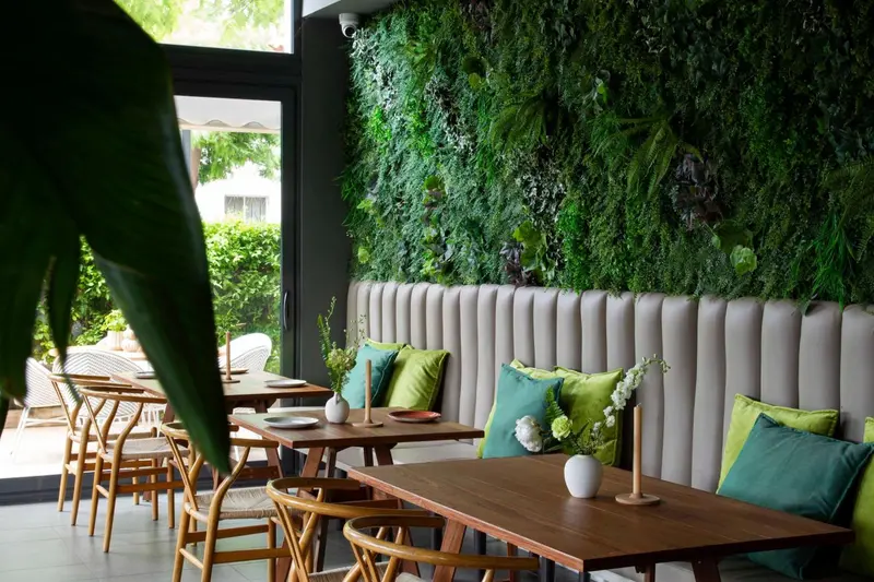 Une salle à manger lumineuse avec des tables en bois et des banquettes moelleuses.