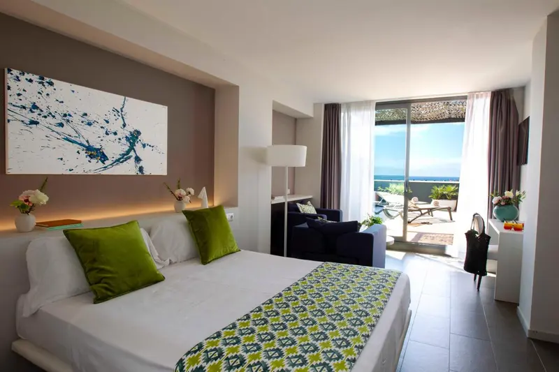 Une chambre lumineuse avec un lit recouvert d'une courtepointe colorée et un accès à une terrasse.