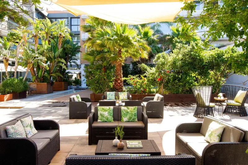 Espace de détente extérieur avec mobilier de jardin et végétation luxuriante.