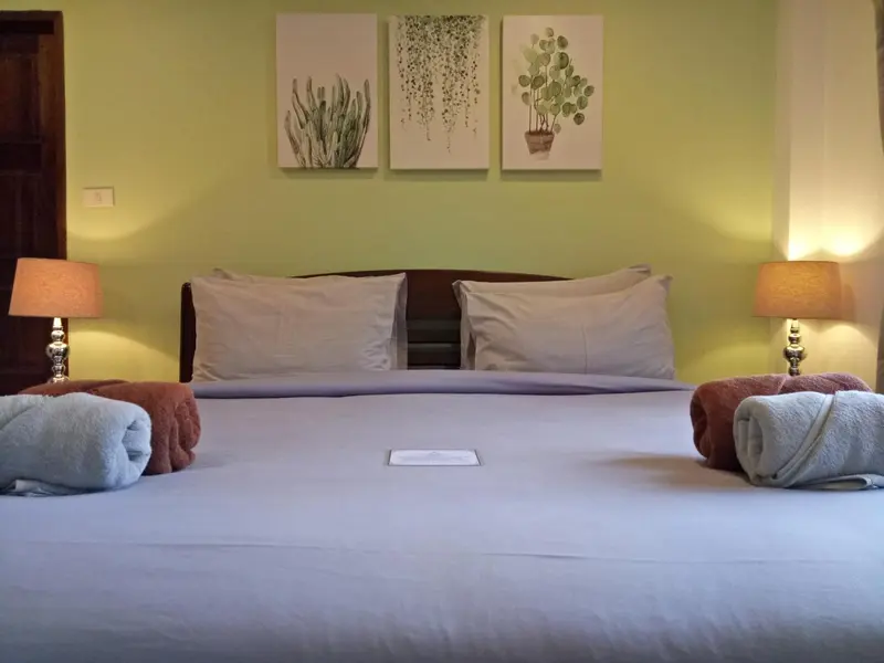 Une chambre avec un grand lit recouvert d'une courtepointe blanche et de coussins.
