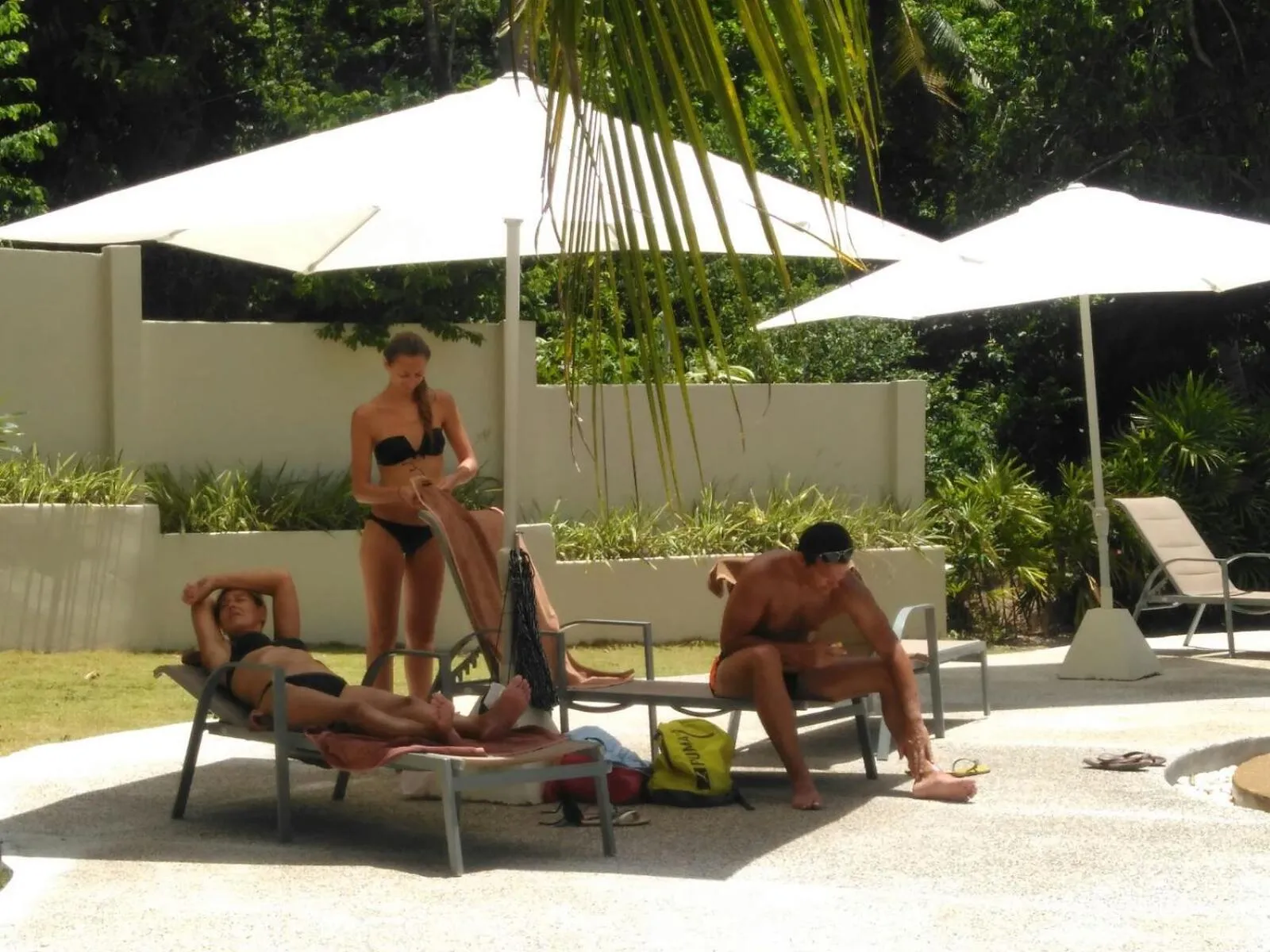 Personnes se relaxant sur des transats près d'une piscine.