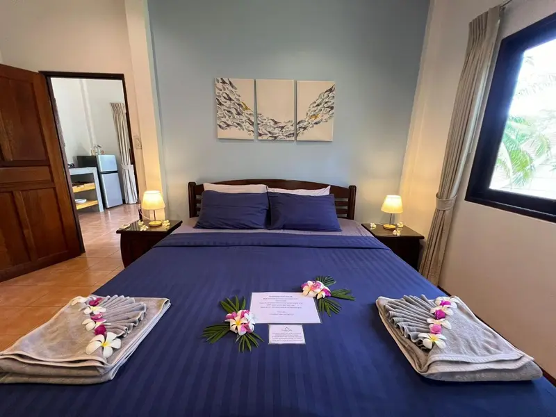 Une chambre avec un grand lit recouvert d'une courtepointe bleue et de fleurs.