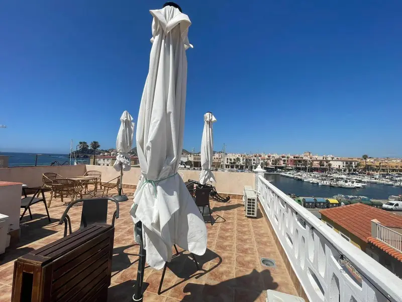 Terrasse aménagée avec parasols et vue sur un port de plaisance.