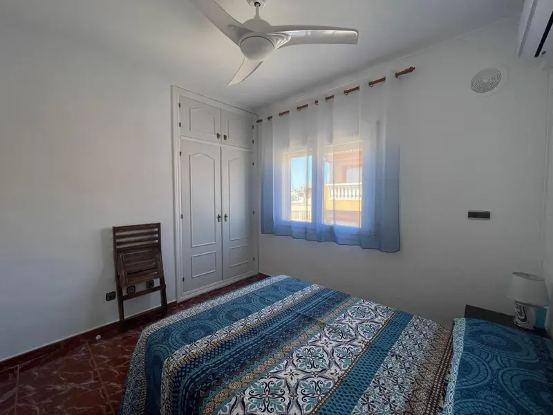 Une chambre lumineuse avec un lit recouvert d'une courtepointe décorative et des rideaux bleus.