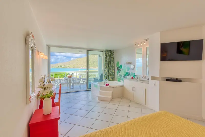 Une chambre lumineuse avec un jacuzzi et une vue sur la mer.