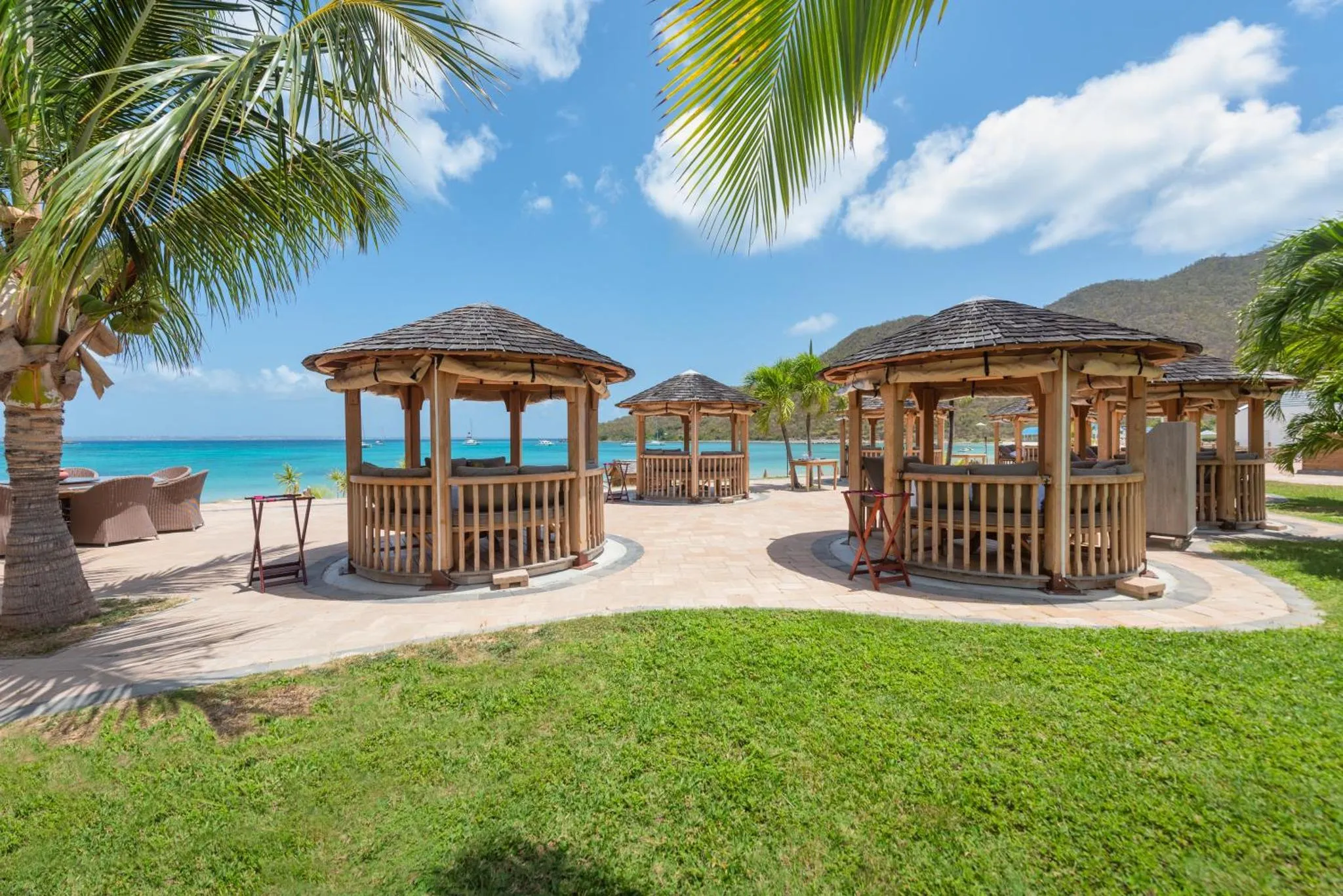 Des cabanes de plage en bois sur une terrasse ensoleillée avec vue sur la mer turquoise.