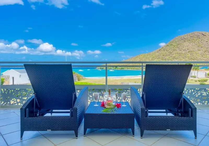 Deux fauteuils de terrasse offrent une vue sur la mer et les collines.