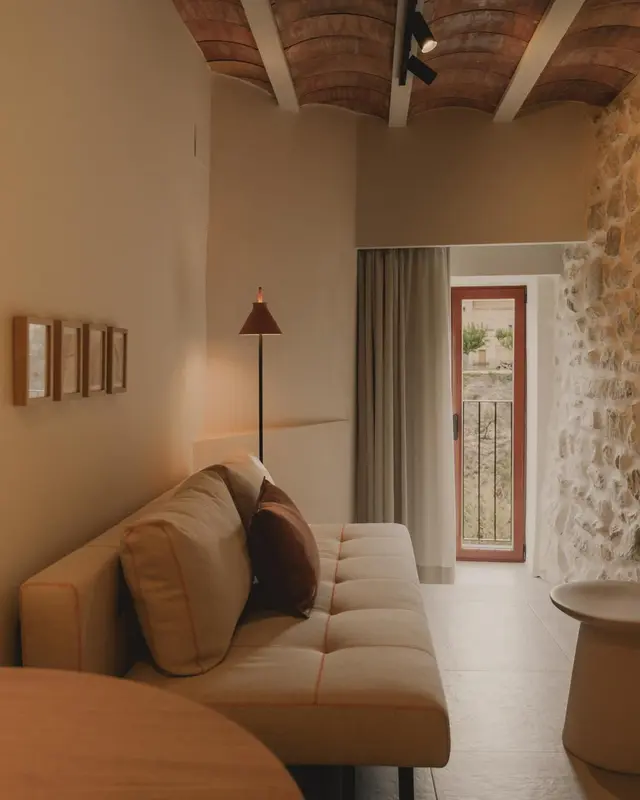 Un canapé beige se trouve dans une pièce aux murs en pierre et au plafond voûté.