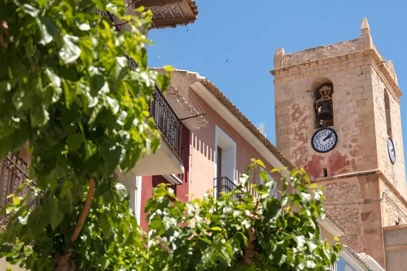 Vue d'une église avec une horloge et des bâtiments environnants.