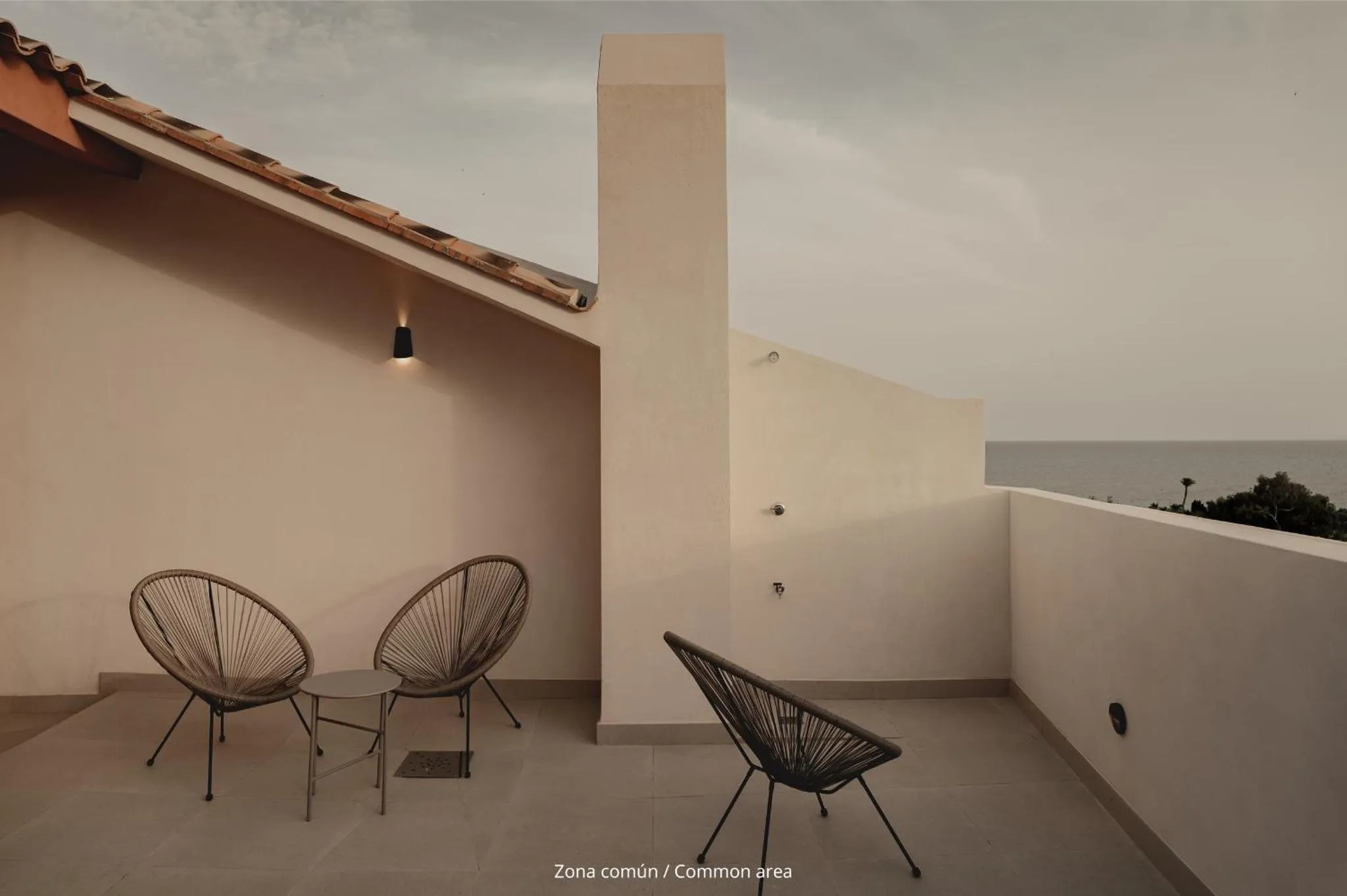 Terrasse aménagée avec des chaises en métal et vue sur la mer.