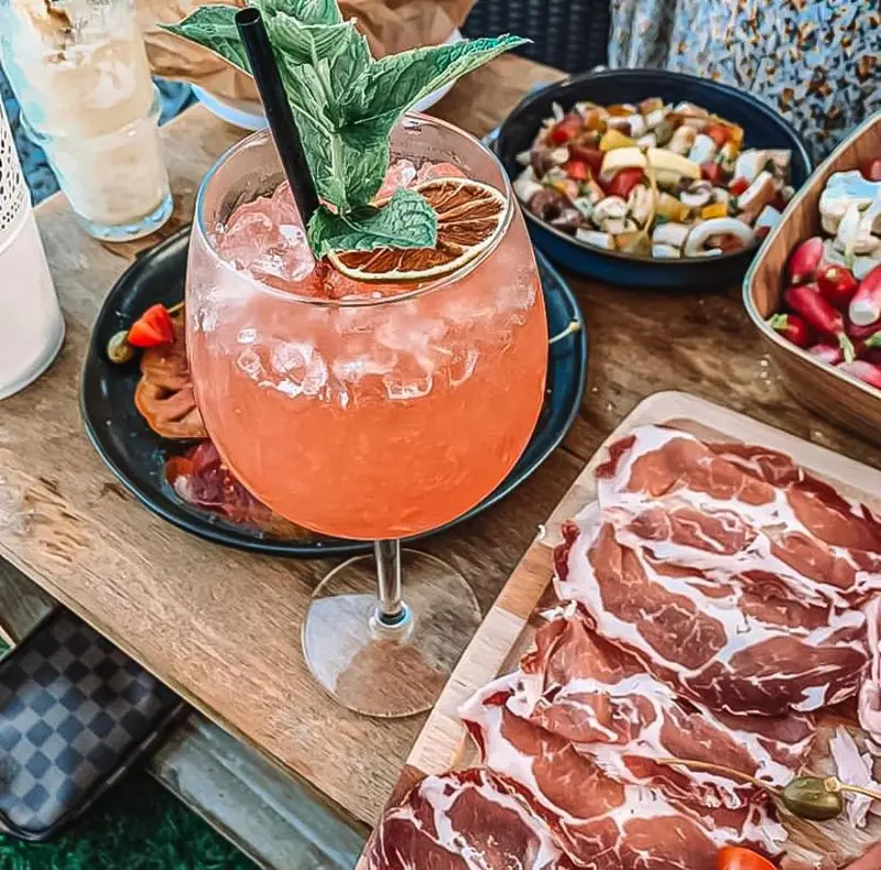 Une table en bois présente des boissons rafraîchissantes et des assiettes de charcuterie.