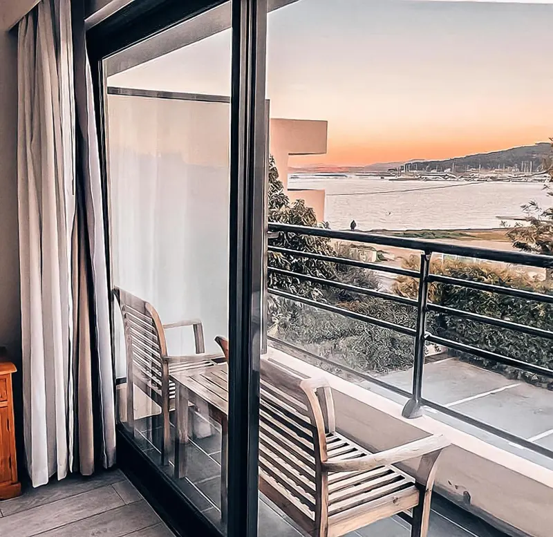 Une terrasse avec mobilier en bois offre une vue sur la mer au coucher du soleil.