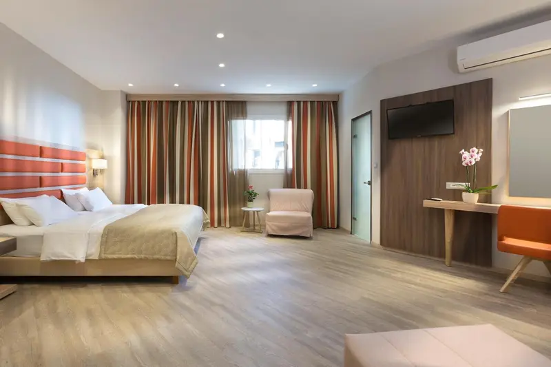 Une chambre lumineuse avec un grand lit et un coin salon.