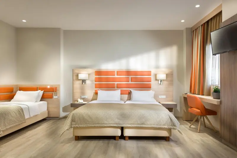 Une chambre d'hôtel lumineuse avec deux lits et un bureau.