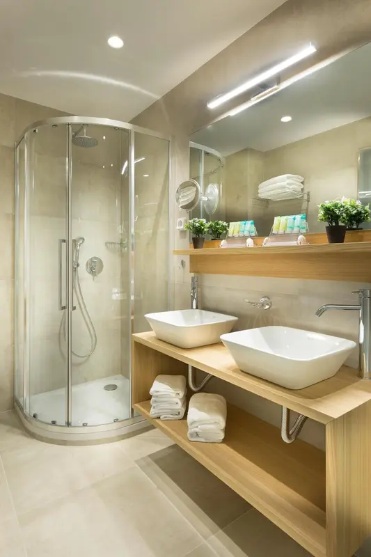 Une salle de bain moderne avec une douche à l'italienne et deux vasques sur un meuble en bois.