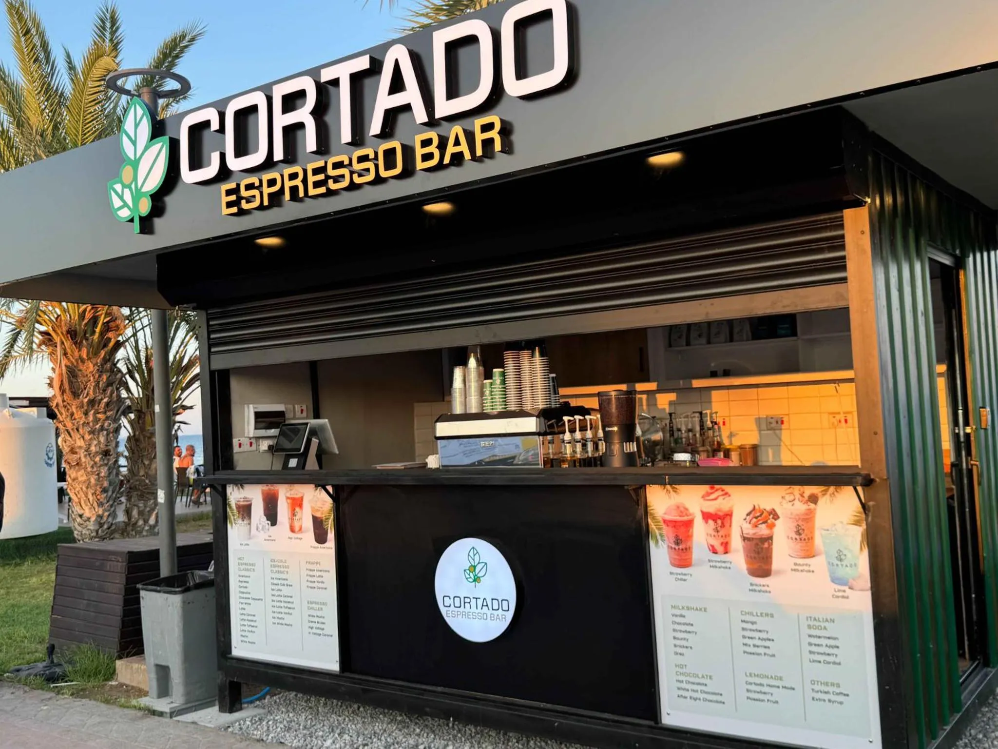 Un comptoir de bar extérieur propose des boissons colorées et des pâtisseries.