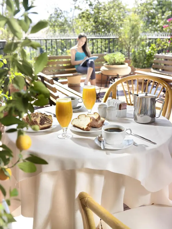 Une table est dressée pour le petit-déjeuner sur une terrasse ensoleillée.