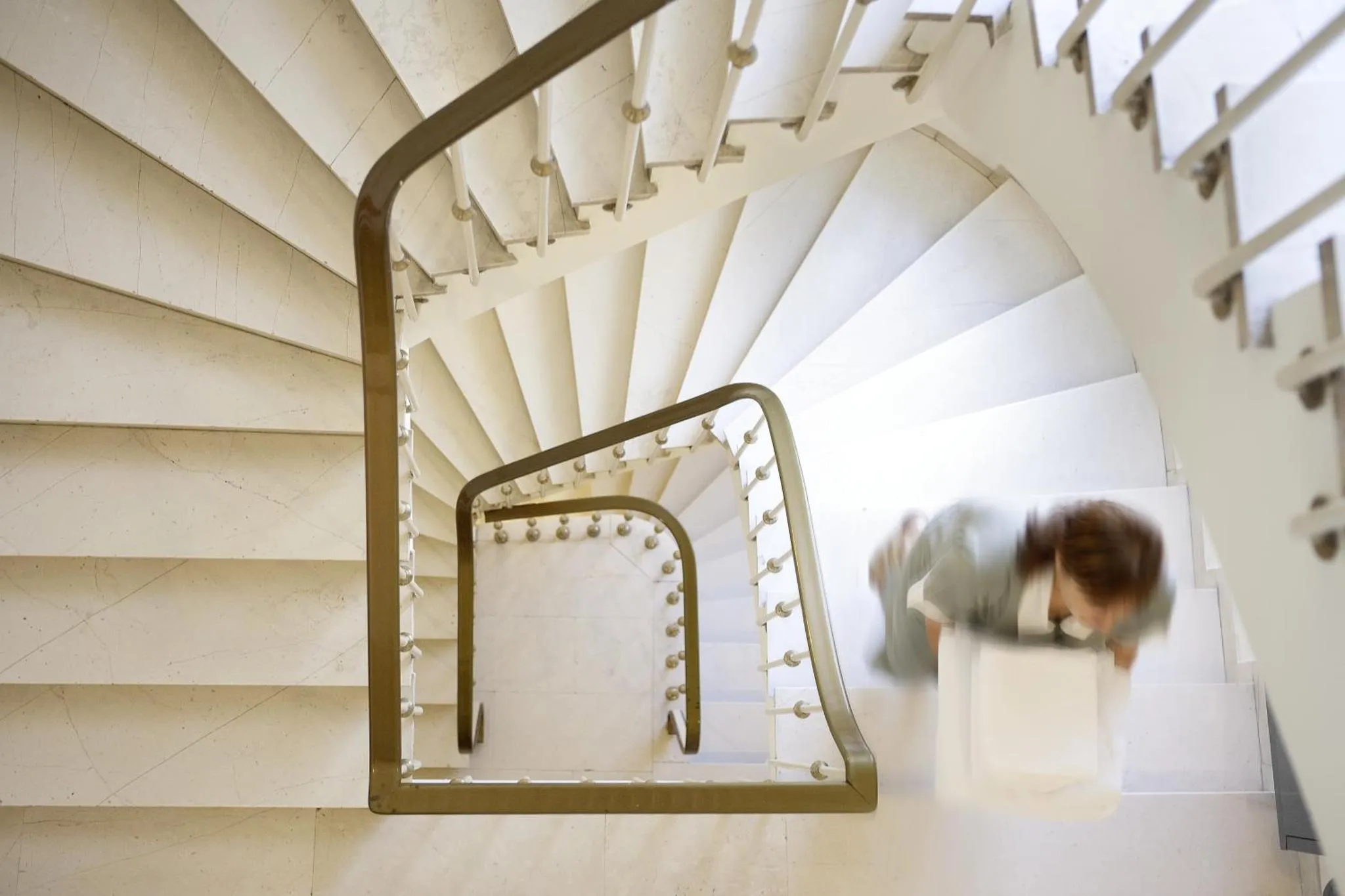 Escalier en colimaçon blanc avec une personne qui monte les marches.