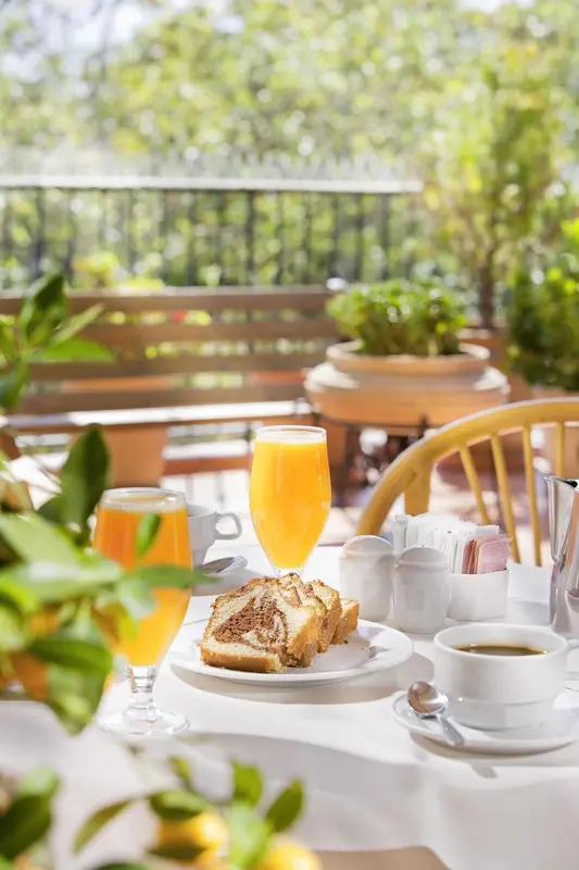 Une table est dressée pour le petit-déjeuner avec des jus d'orange, du pain et du café.