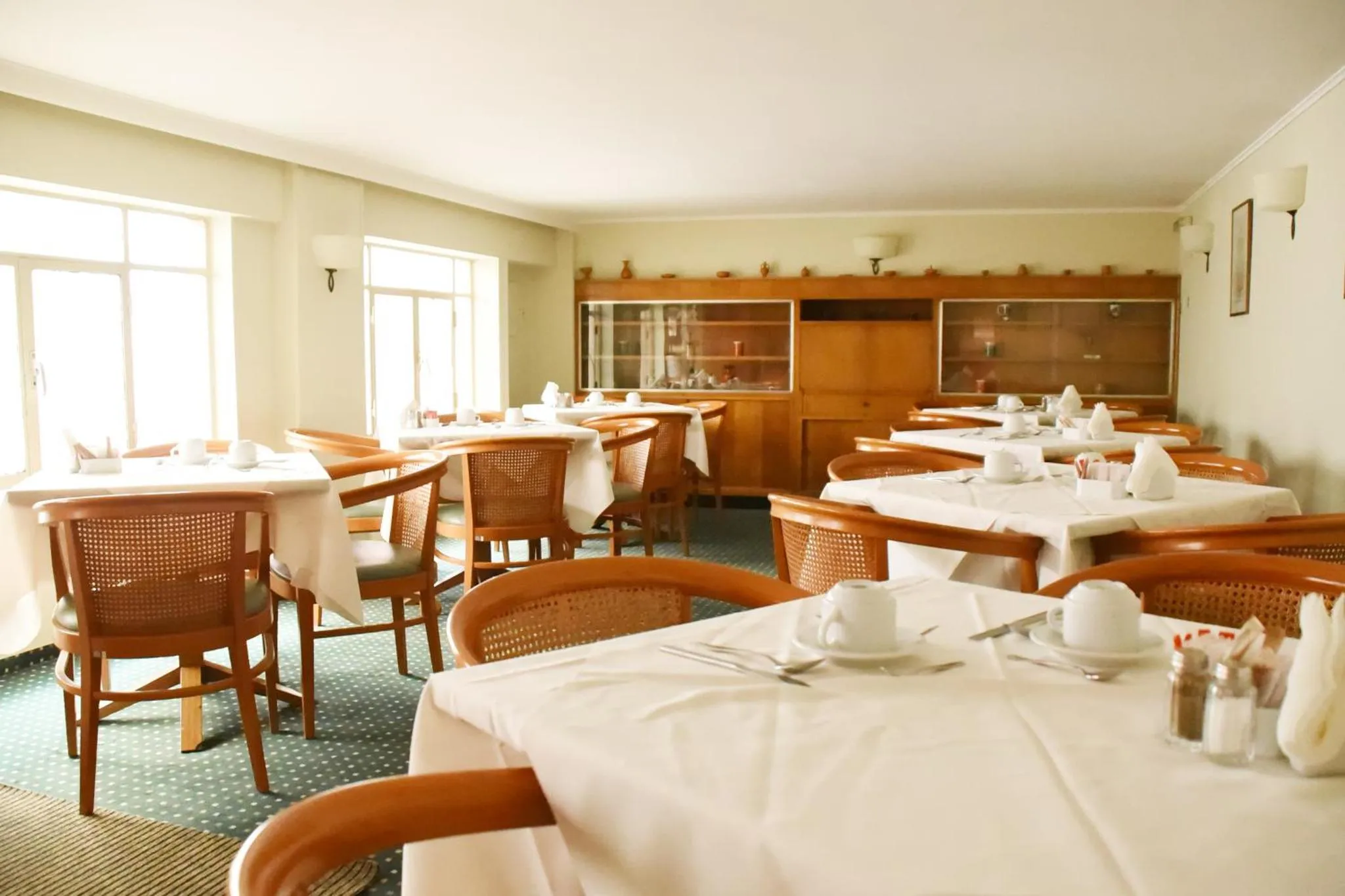 Une salle lumineuse avec des tables dressées pour le repas.