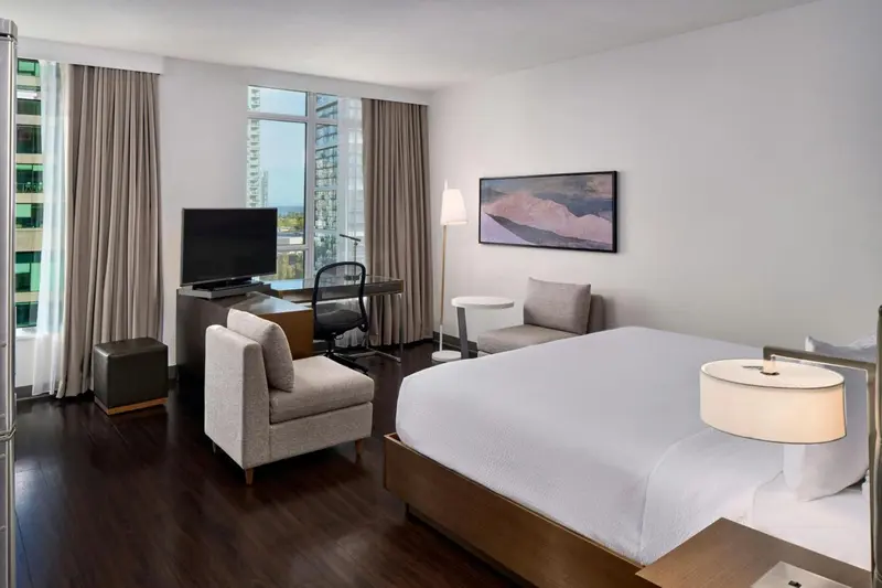 Une chambre d'hôtel moderne avec un lit, un fauteuil et un bureau.