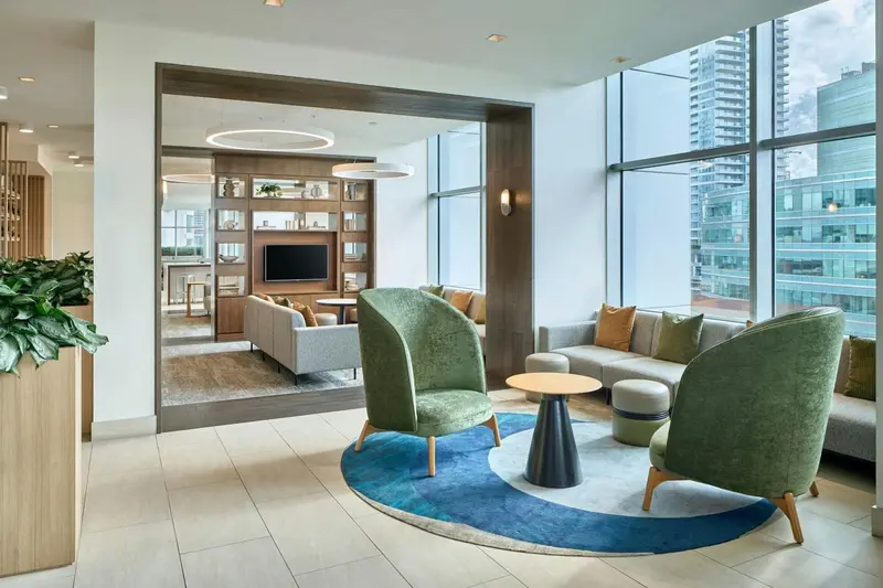 Espace de détente intérieur avec canapés et fauteuils près d'une grande fenêtre.