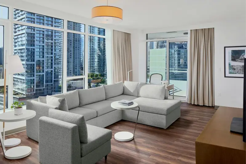 Un salon moderne avec un grand canapé d'angle et une vue sur la ville.