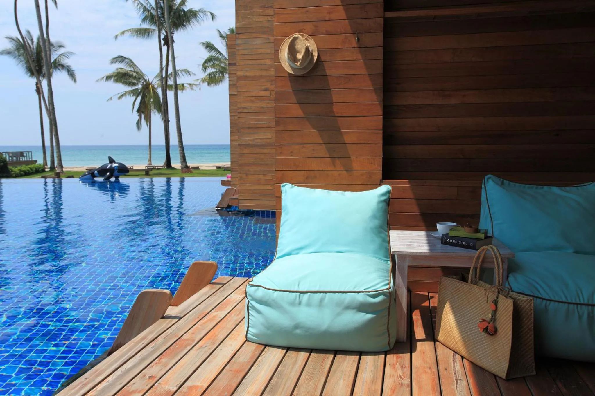 Terrasse avec mobilier de détente et piscine turquoise.