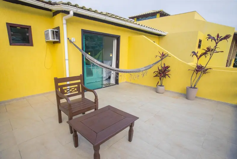 Terrasse avec mobilier en bois et hamac suspendu.