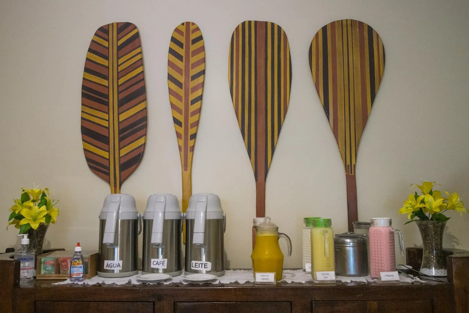Des pagaies décoratives ornent un mur au-dessus d'un buffet avec des boissons et des thermos.