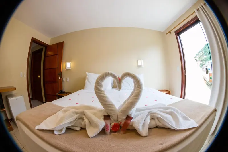 Une chambre lumineuse avec un lit décoré de serviettes en forme de cœur.