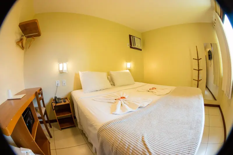 Une chambre lumineuse avec un lit recouvert d'une courtepointe blanche et de serviettes décoratives.