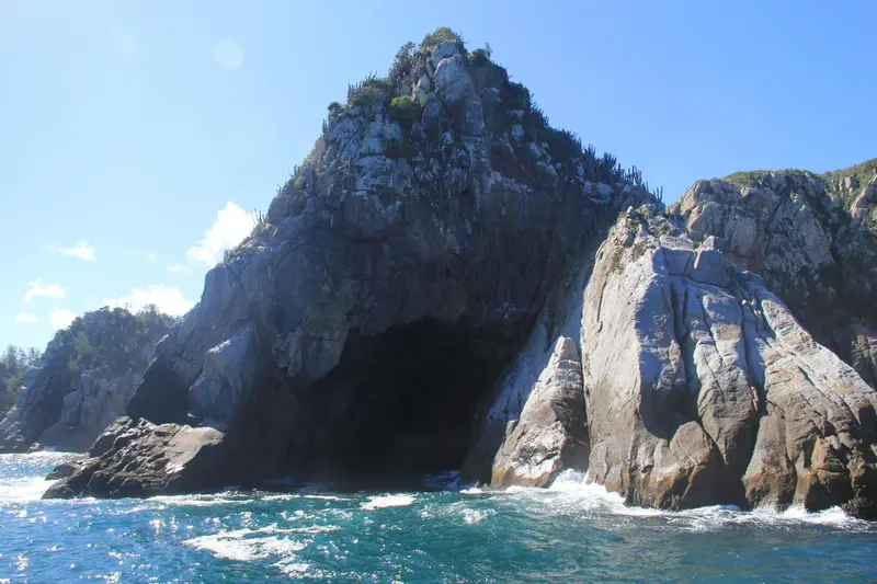 Côte rocheuse escarpée plongeant dans une mer turquoise sous un ciel bleu.