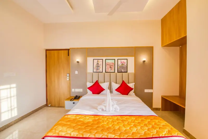Une chambre lumineuse avec un grand lit décoré de coussins rouges et d'une serviette en forme de cygne.