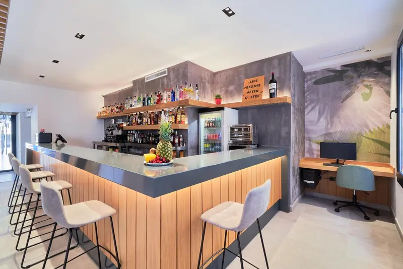 Un comptoir de bar moderne avec des tabourets et une décoration tropicale.