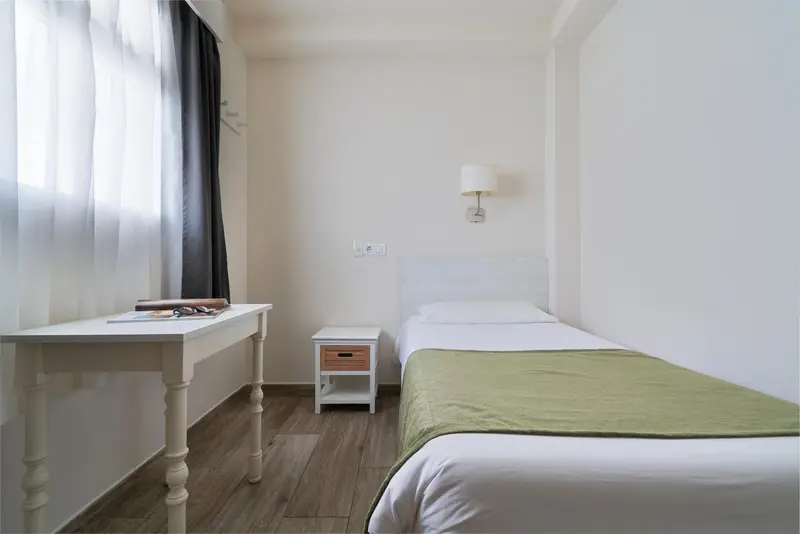 Une chambre lumineuse avec un lit simple et un bureau.