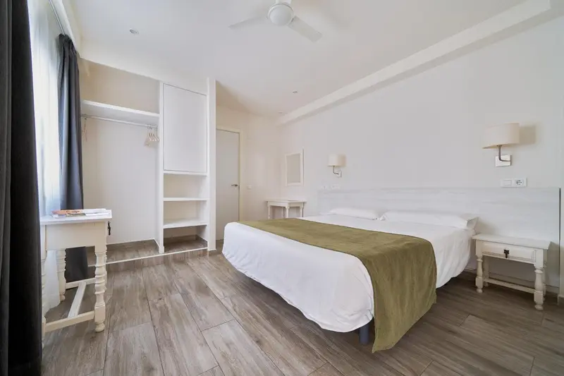 Une chambre lumineuse avec un lit recouvert d'une couverture verte.