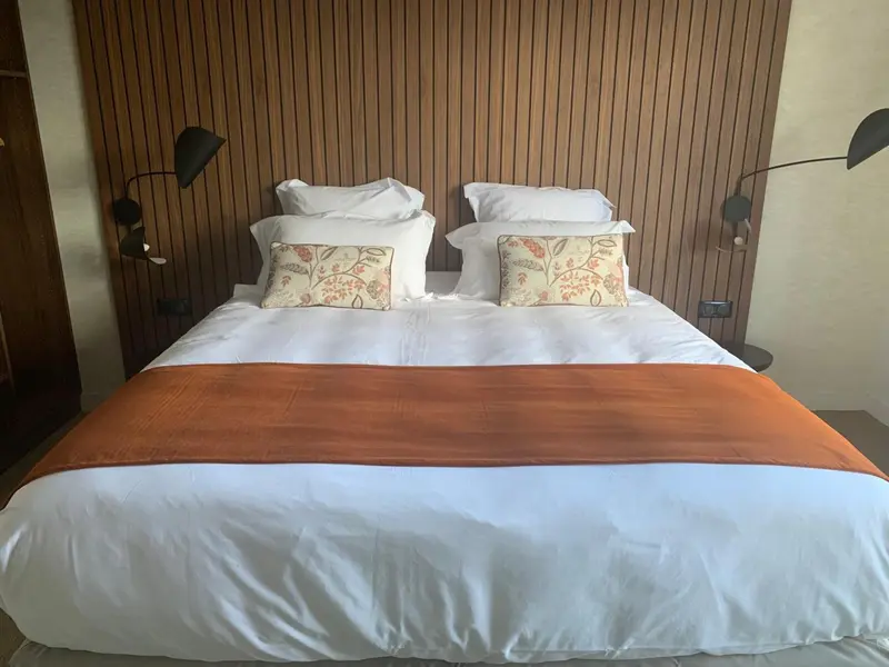 Un lit double est fait avec une couverture orange et des oreillers blancs.