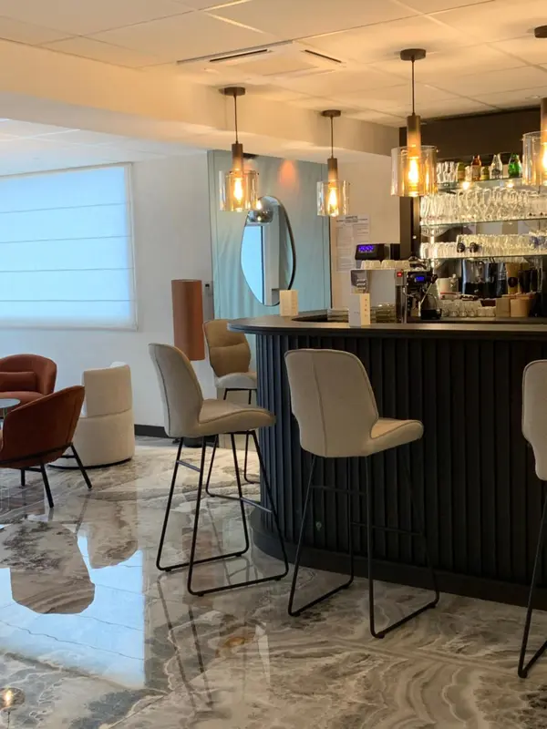 Un bar moderne avec des tabourets et un comptoir en bois sombre.