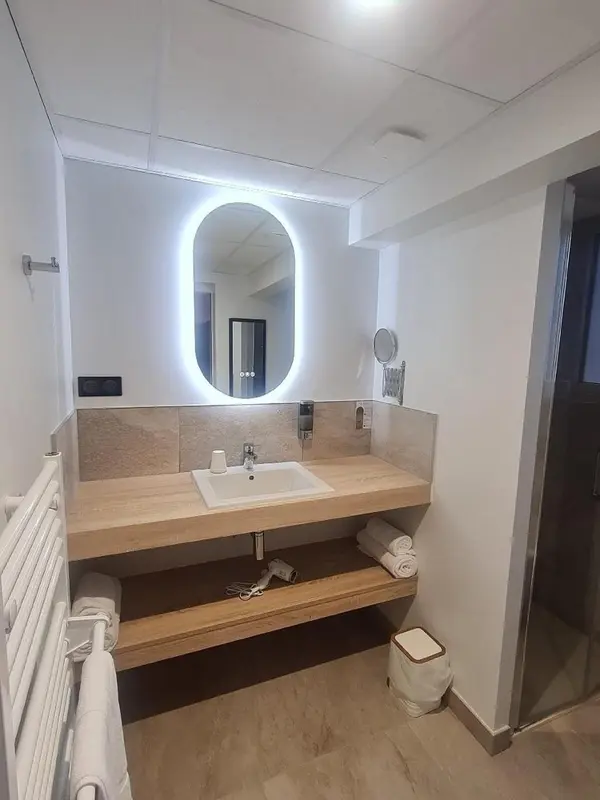 Une salle de bain moderne avec un grand miroir lumineux au-dessus du lavabo.
