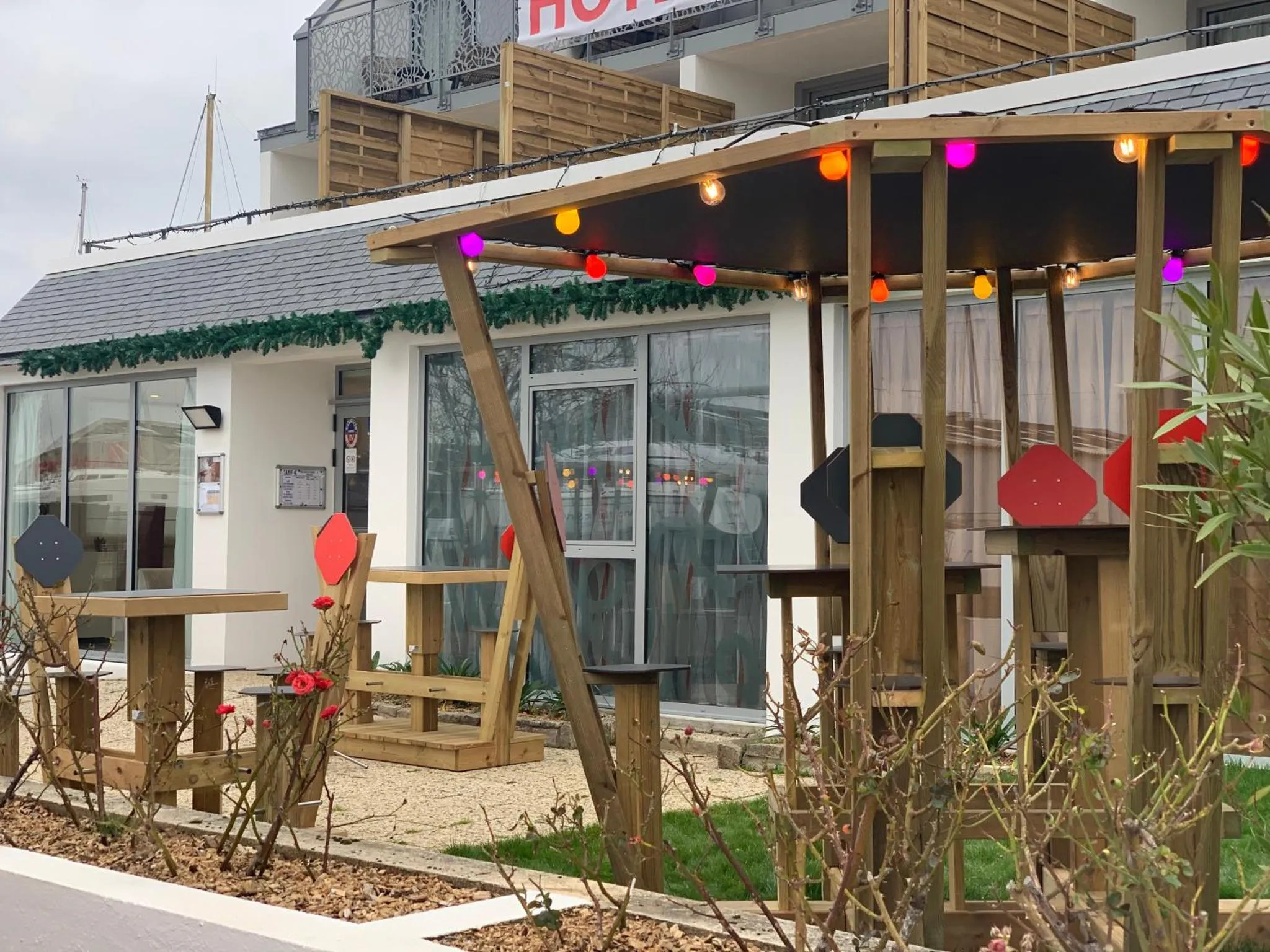 Terrasse ombragée avec tables et chaises devant un bâtiment.