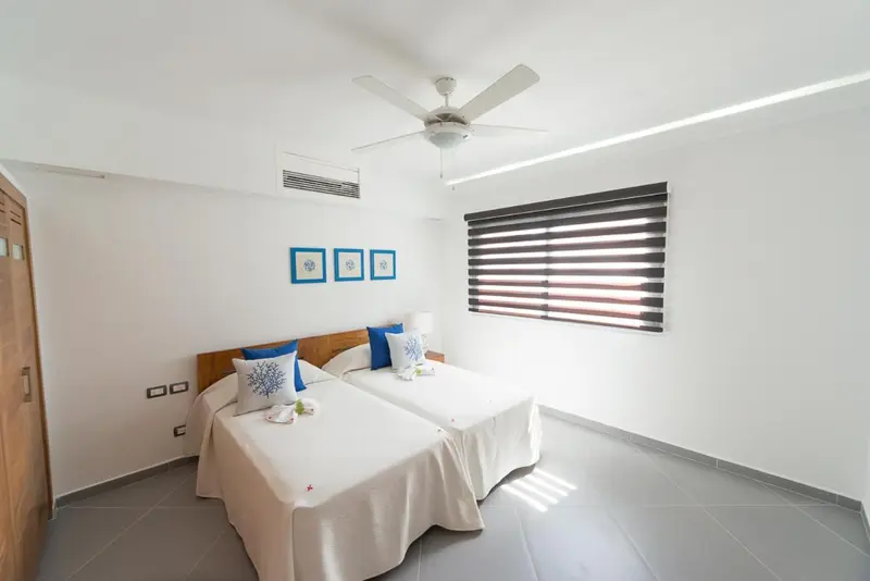 Chambre lumineuse avec deux lits simples et décoration marine.