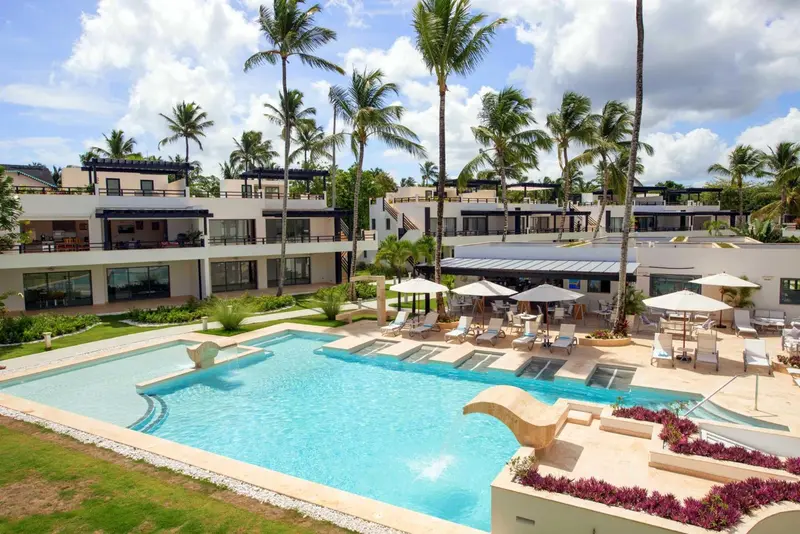 Vue aérienne d'une piscine et d'un bâtiment blanc entouré de végétation tropicale.