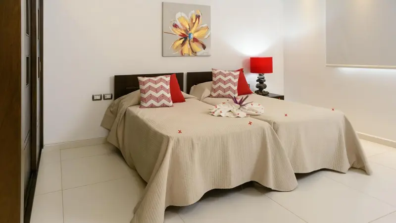 Une chambre lumineuse avec un grand lit décoré de coussins et d'une couverture.
